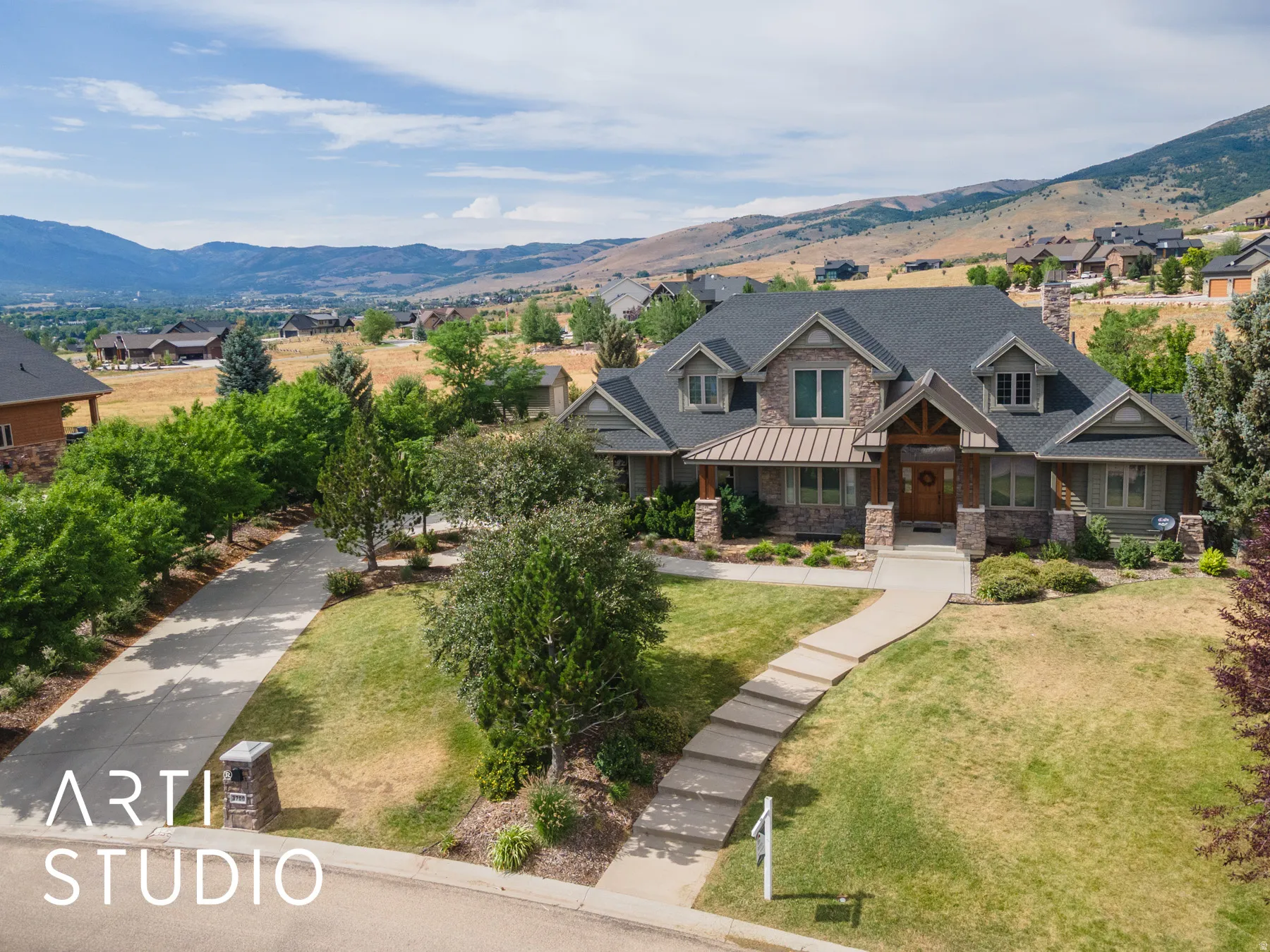 View of front of home with stone siding, a front yard, a mountain view, and a chimney