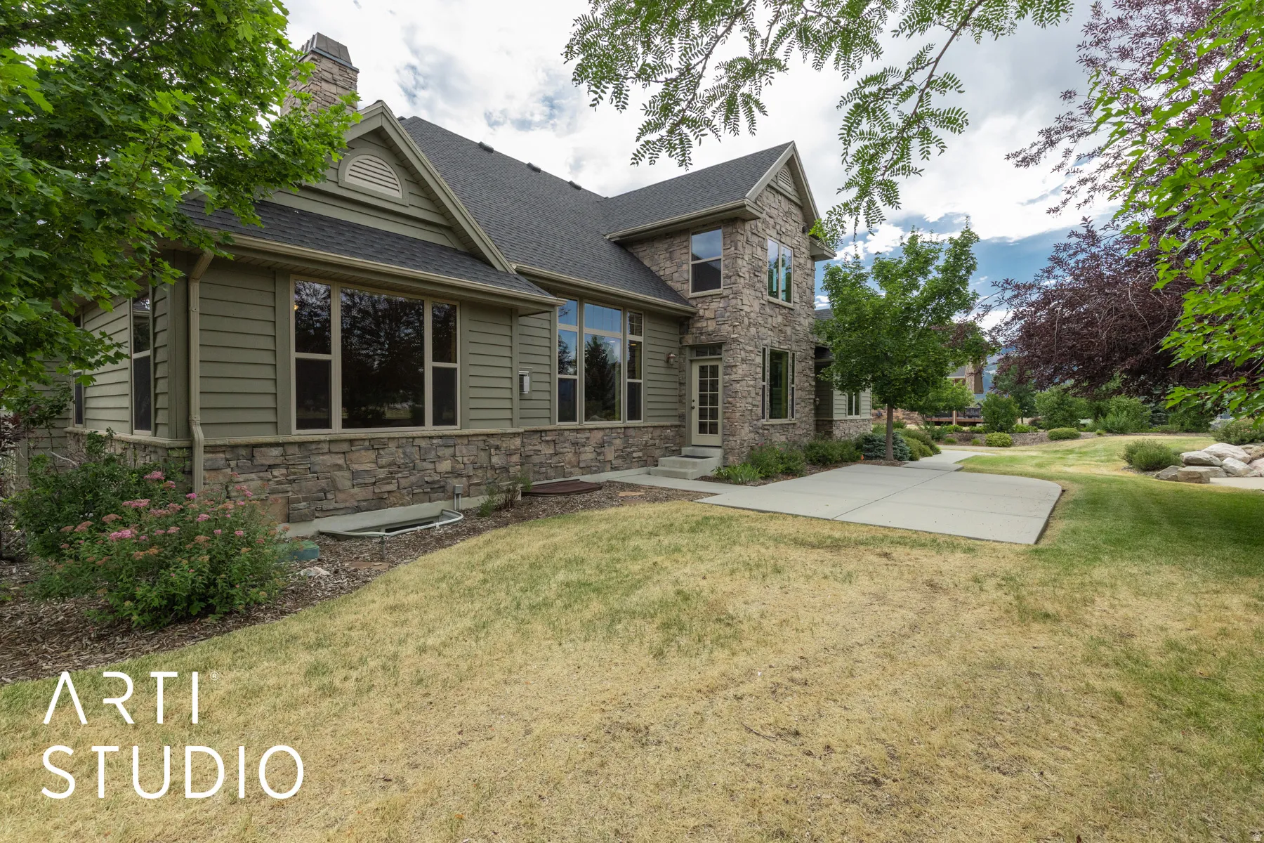 View of front of home with stone siding, a front yard, a shingled roof, a chimney, and entry steps