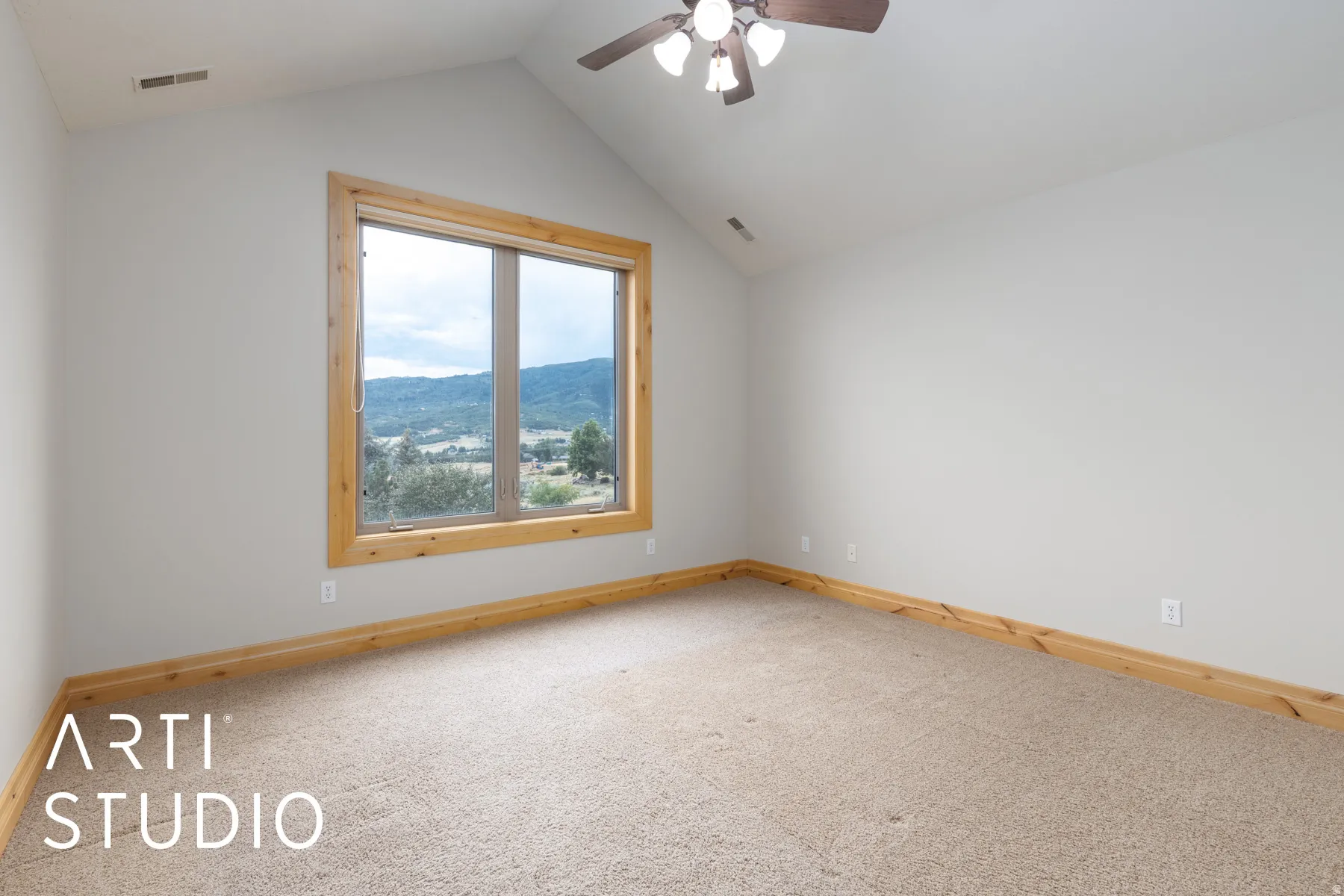 Carpeted spare room featuring vaulted ceiling and a ceiling fan