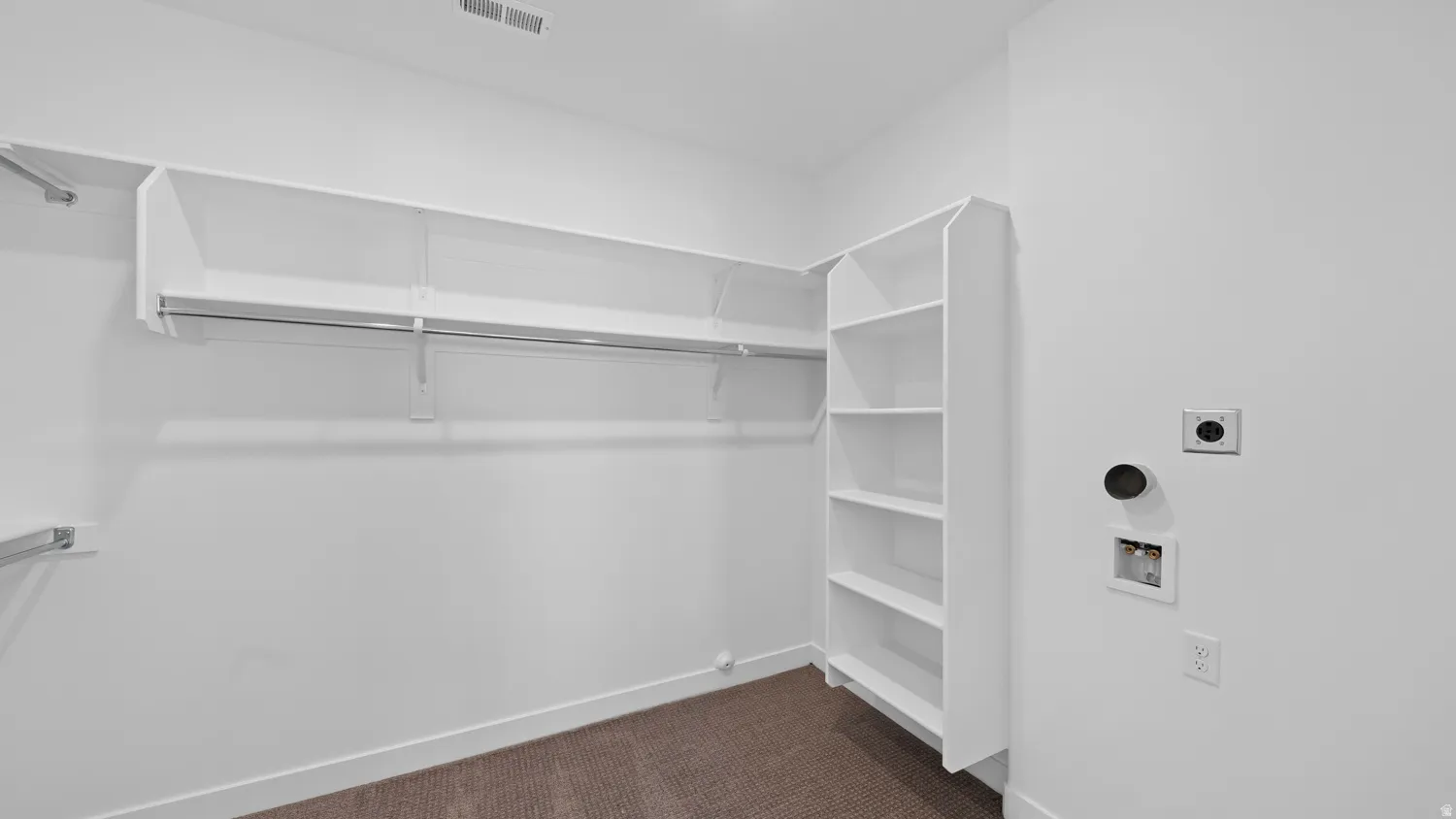 Walk in closet featuring dark carpet