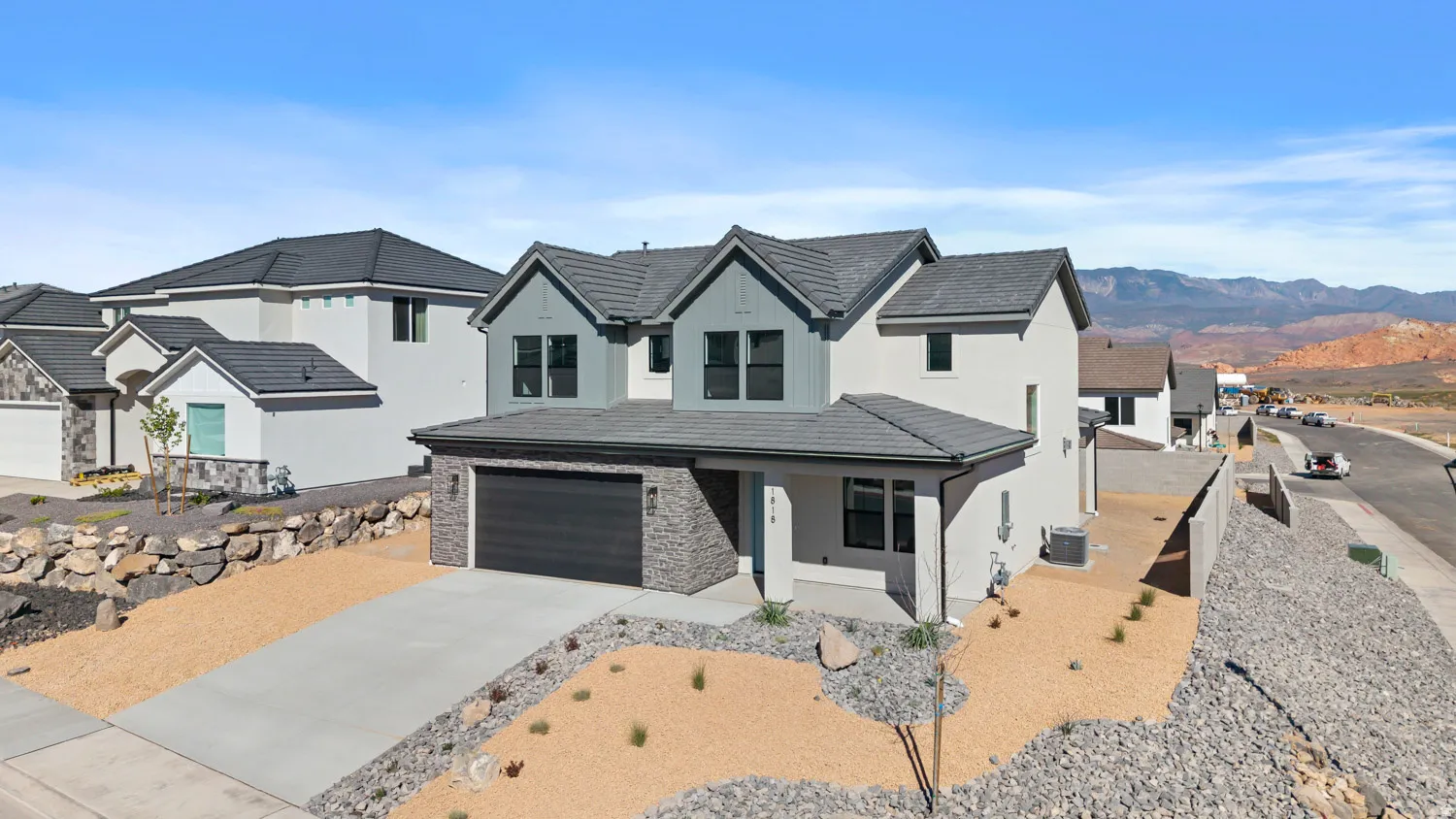 Modern farmhouse featuring concrete driveway, stucco siding, an attached garage, a porch, and stone siding