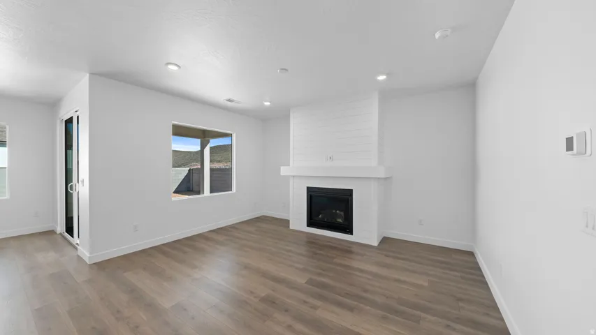 Unfurnished living room with dark wood-style flooring, a large fireplace, and recessed lighting