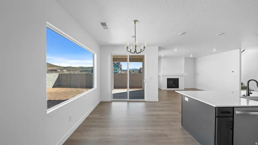 Kitchen with hanging lights, a fireplace, stainless steel dishwasher, dark wood-style floors, and open floor plan