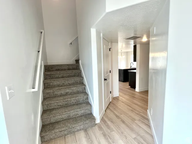 Stairs featuring a textured ceiling and wood finished floors