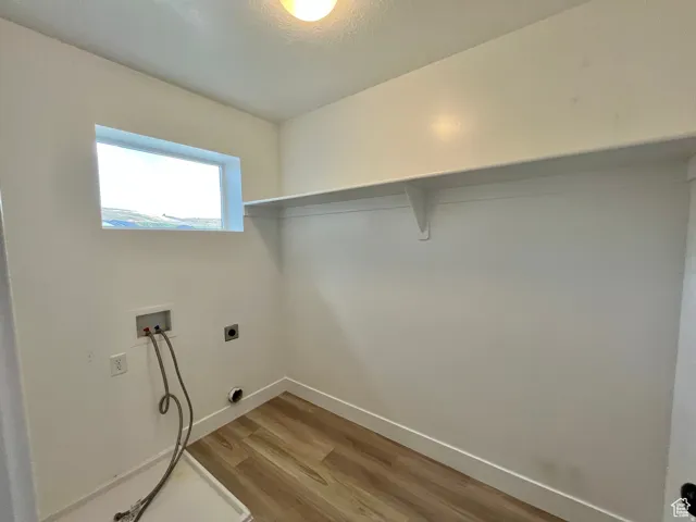 Laundry area with light wood-style flooring, hookup for a washing machine, and hookup for an electric dryer