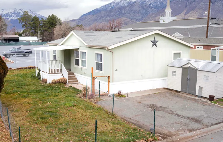 View of front of home featuring a mountain view, a front lawn, and a storage unit