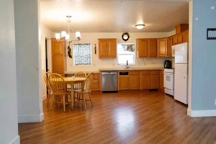 Kitchen with light countertops, pendant lighting, white appliances, a chandelier, and light wood-type flooring