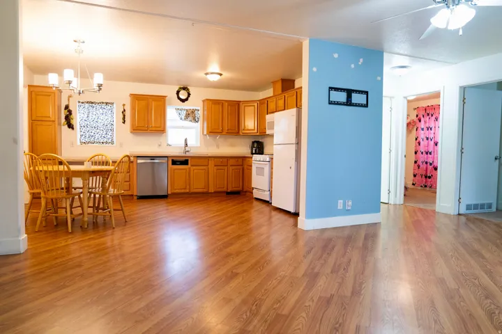 Kitchen with light countertops, a chandelier, white appliances, hanging light fixtures, and light wood finished floors