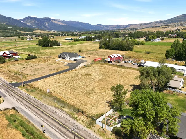 Expansive property featuring a contemporary residence with a dark roof, paved driveway, and surrounding agricultural land
