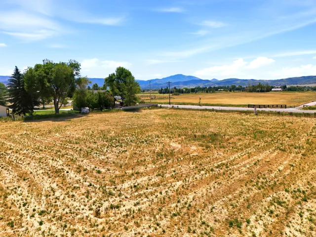 Expansive open land with distant mountain ranges and a partially visible residential structure