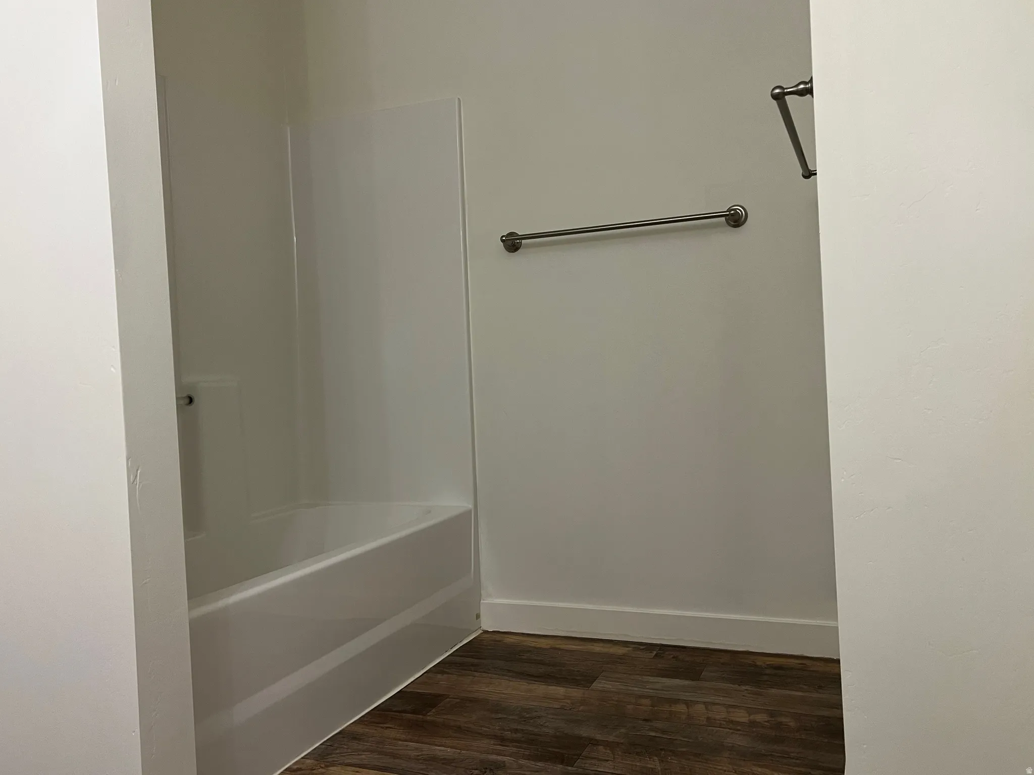 Bathroom featuring dark wood-style flooring and shower / bathtub combination