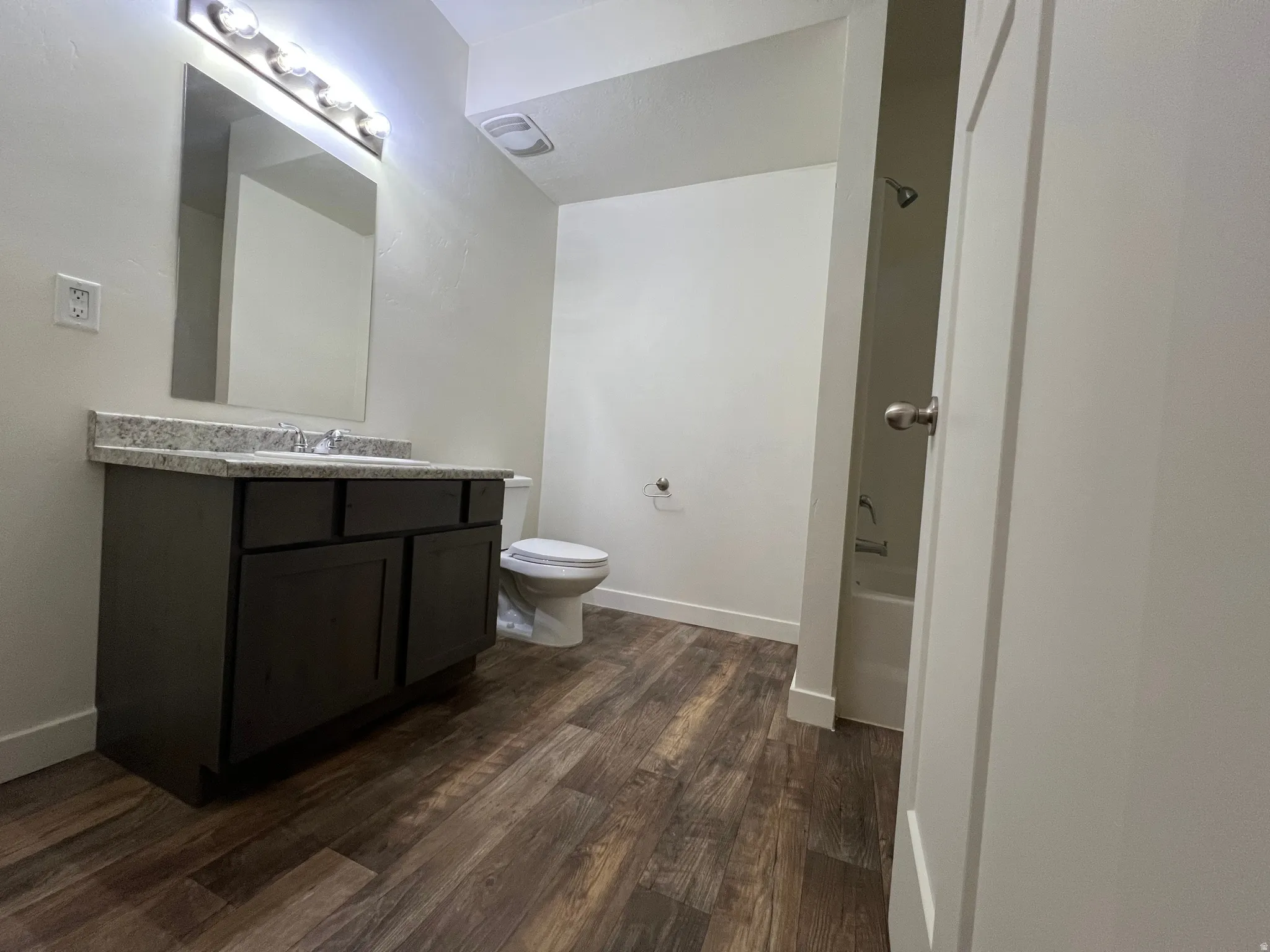 Bathroom with vanity, dark wood-style floors, and tub / shower combination
