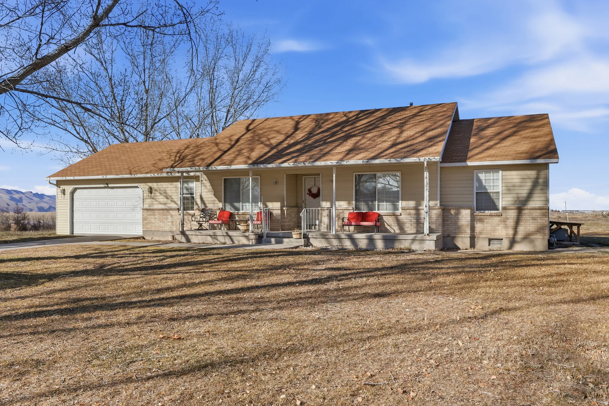 View of front of property featuring brick siding, covered porch, and an attached garage