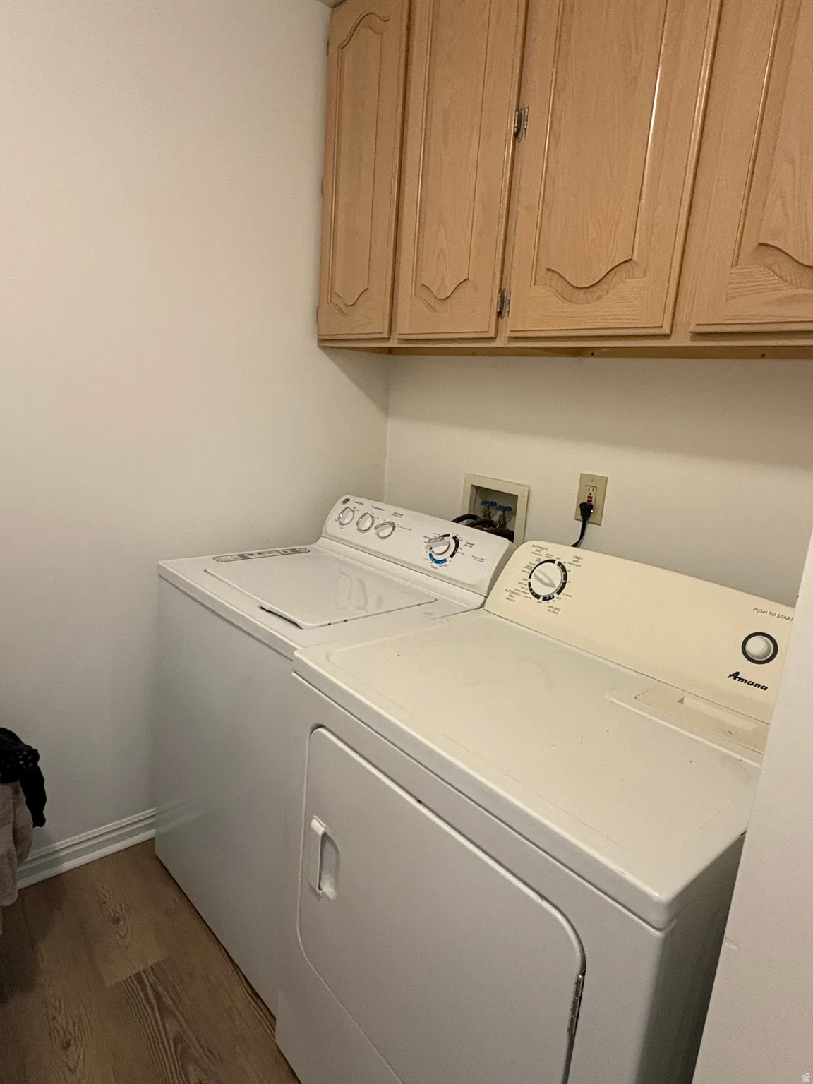 Washroom featuring cabinet space, wood finished floors, and separate washer and dryer