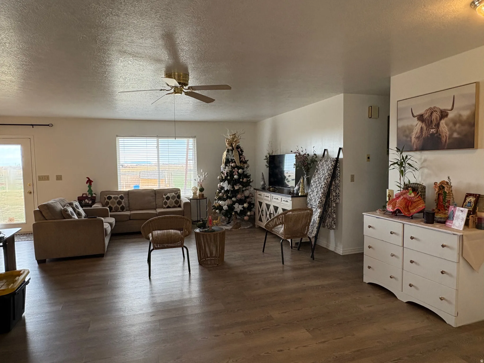 Living area with a textured ceiling, dark wood finished floors, and ceiling fan
