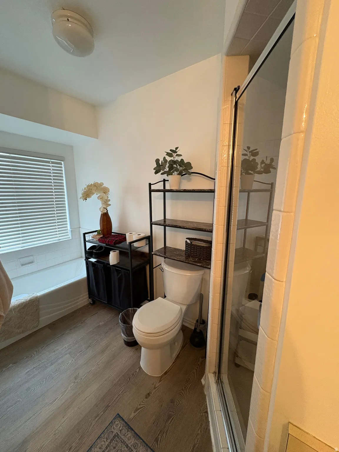 Bathroom with wood finished floors, a shower stall, and a bathtub