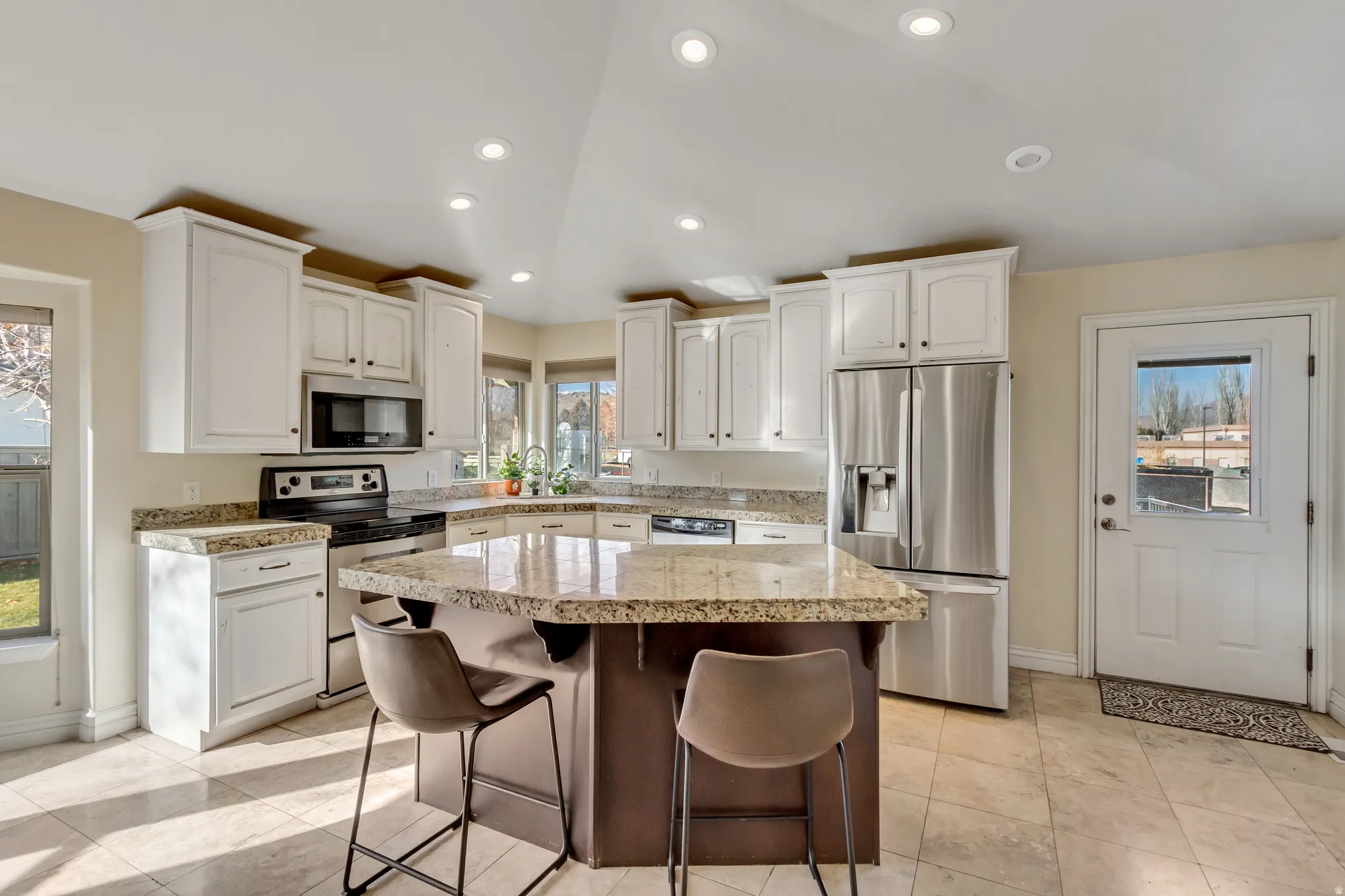 Kitchen with appliances with stainless steel finishes, plenty of natural light, a breakfast bar, recessed lighting, and a kitchen island
