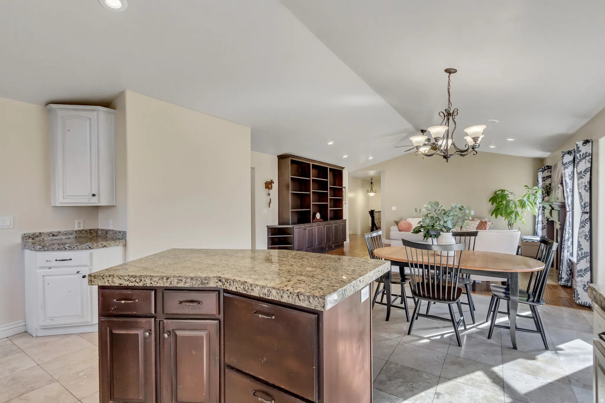 Kitchen featuring dark brown cabinets, a kitchen island, hanging light fixtures, lofted ceiling, and a chandelier