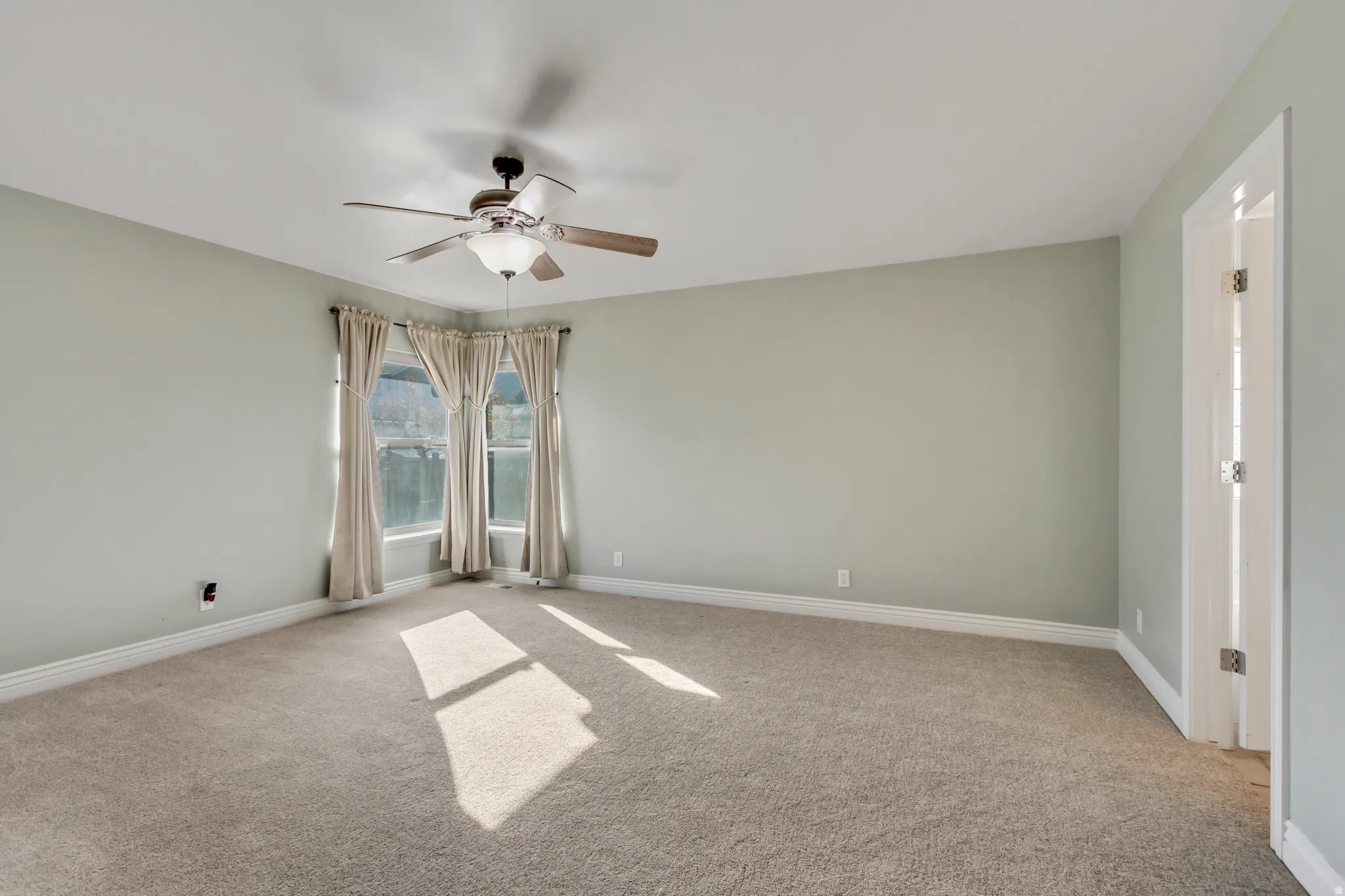 Unfurnished room with light carpet and a ceiling fan