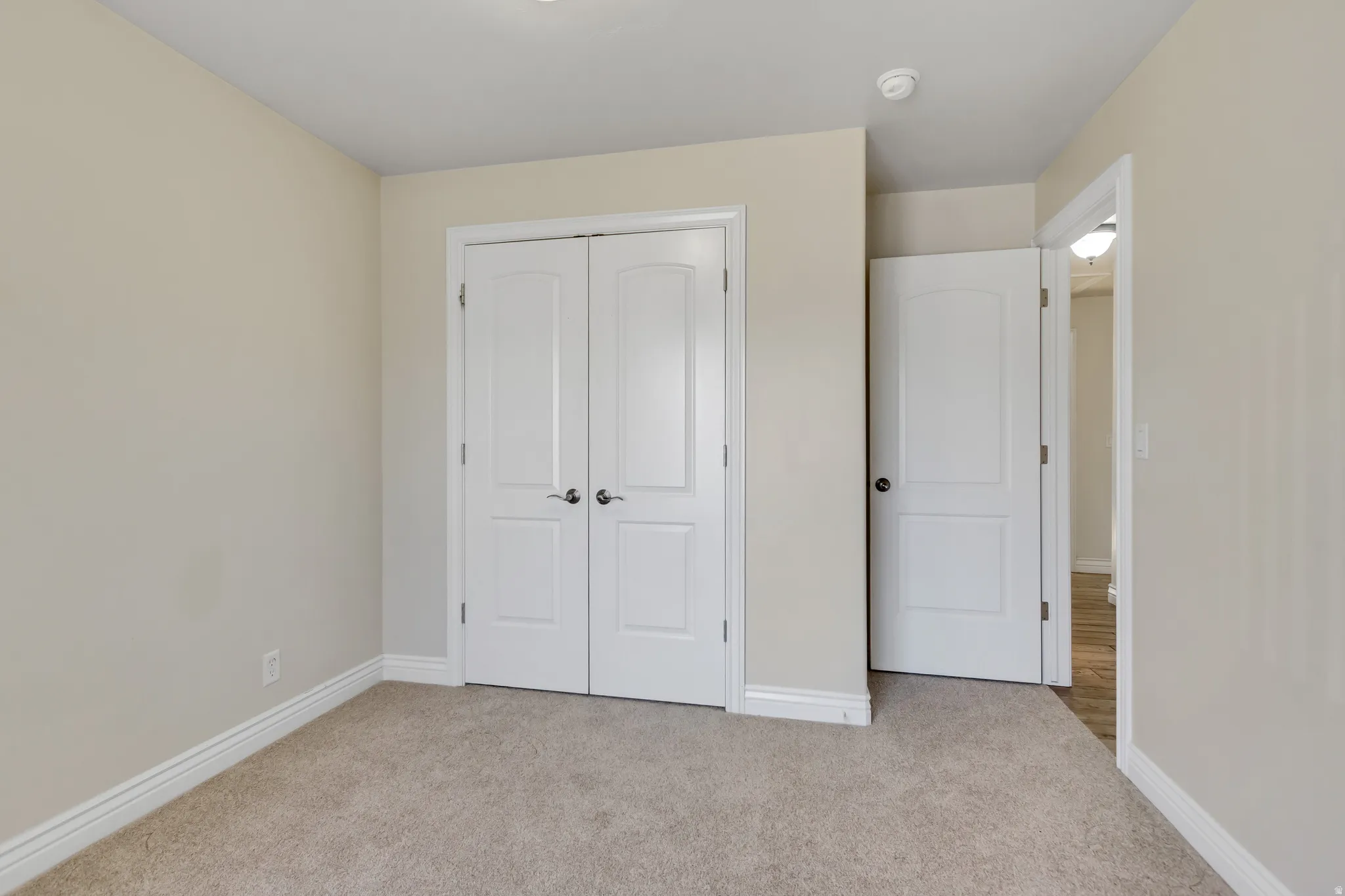 Unfurnished bedroom with light carpet and a closet