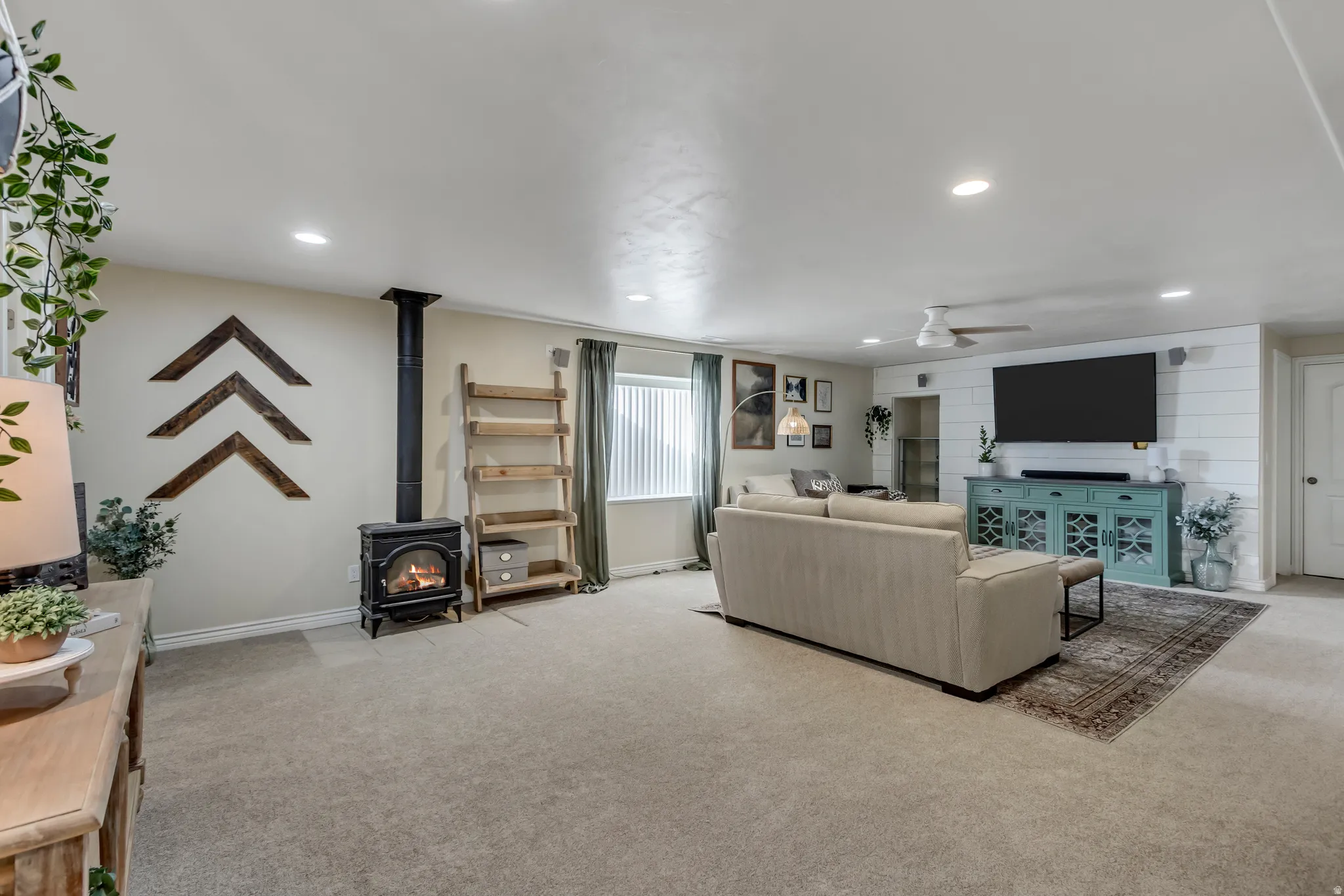 Living room featuring a wood stove, light colored carpet, recessed lighting, and a ceiling fan
