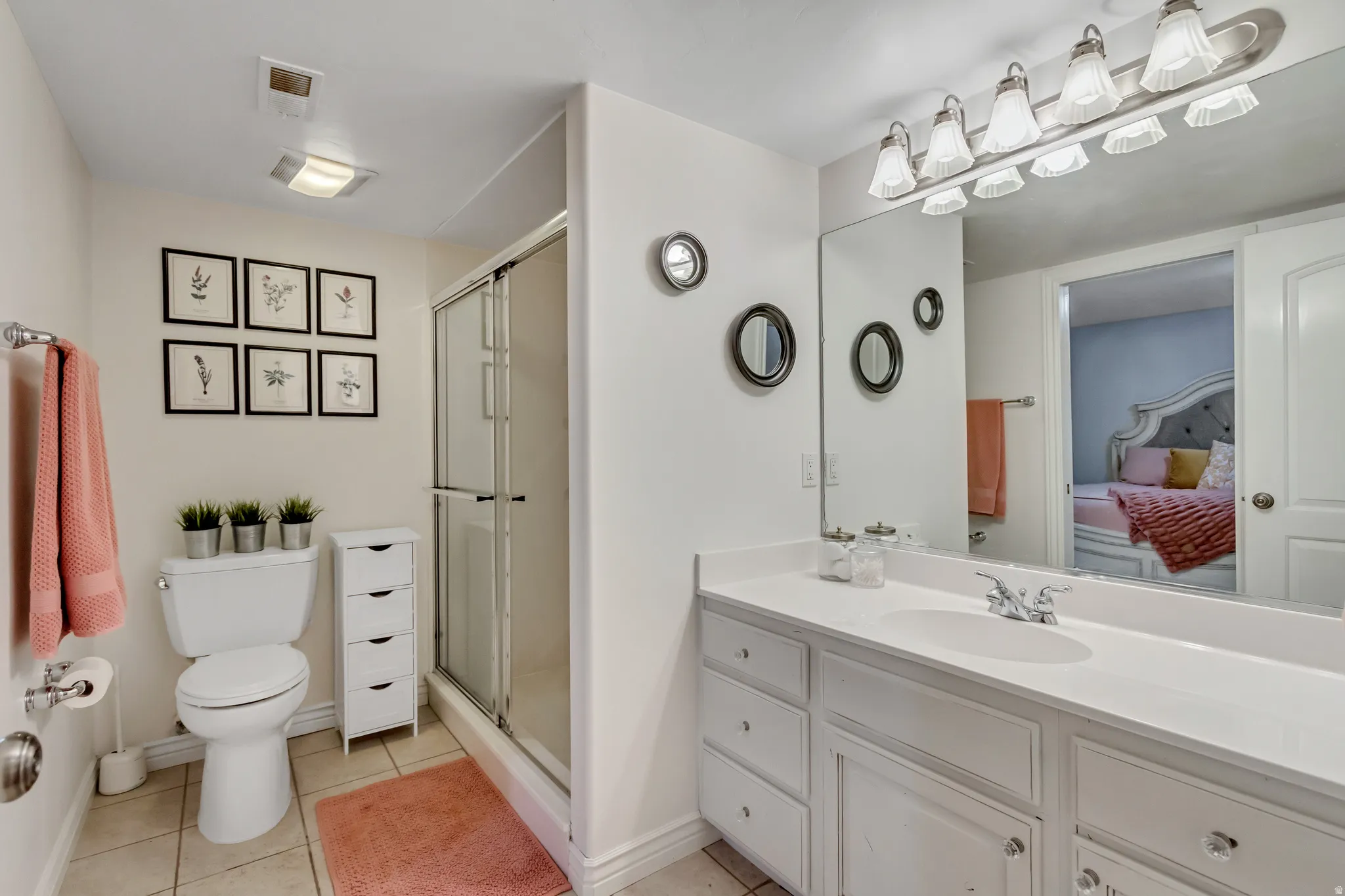 Ensuite bathroom featuring vanity, a shower stall, and light tile patterned flooring