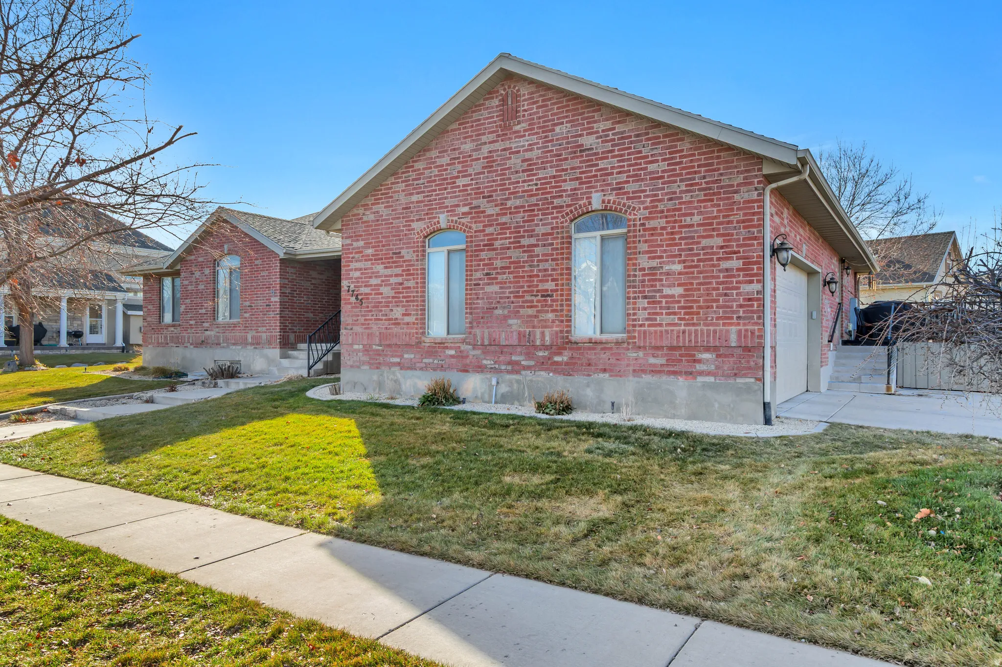 View of front of home with brick siding, a front yard, and a garage
