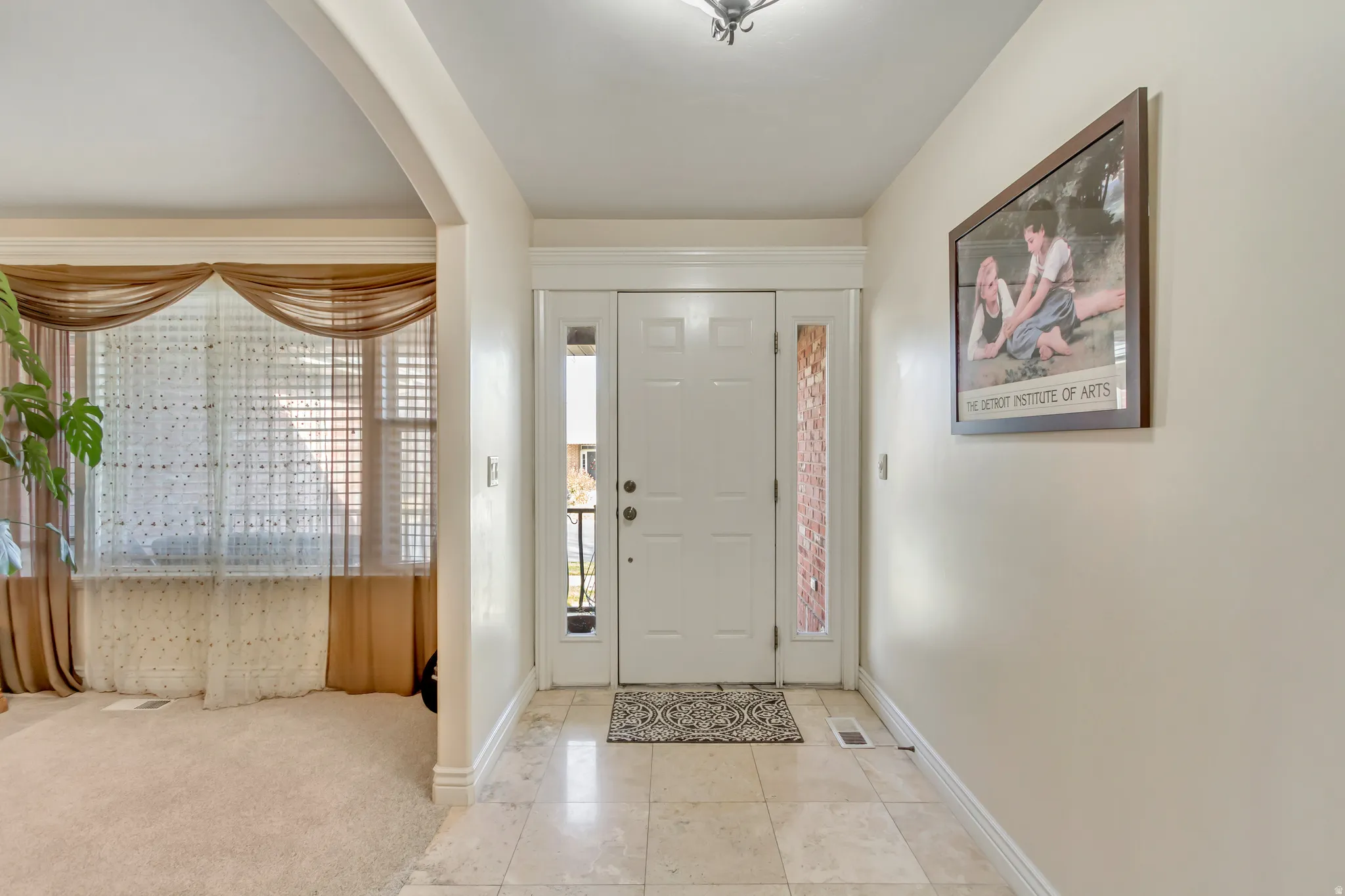 Tiled entrance foyer featuring arched walkways and carpet floors