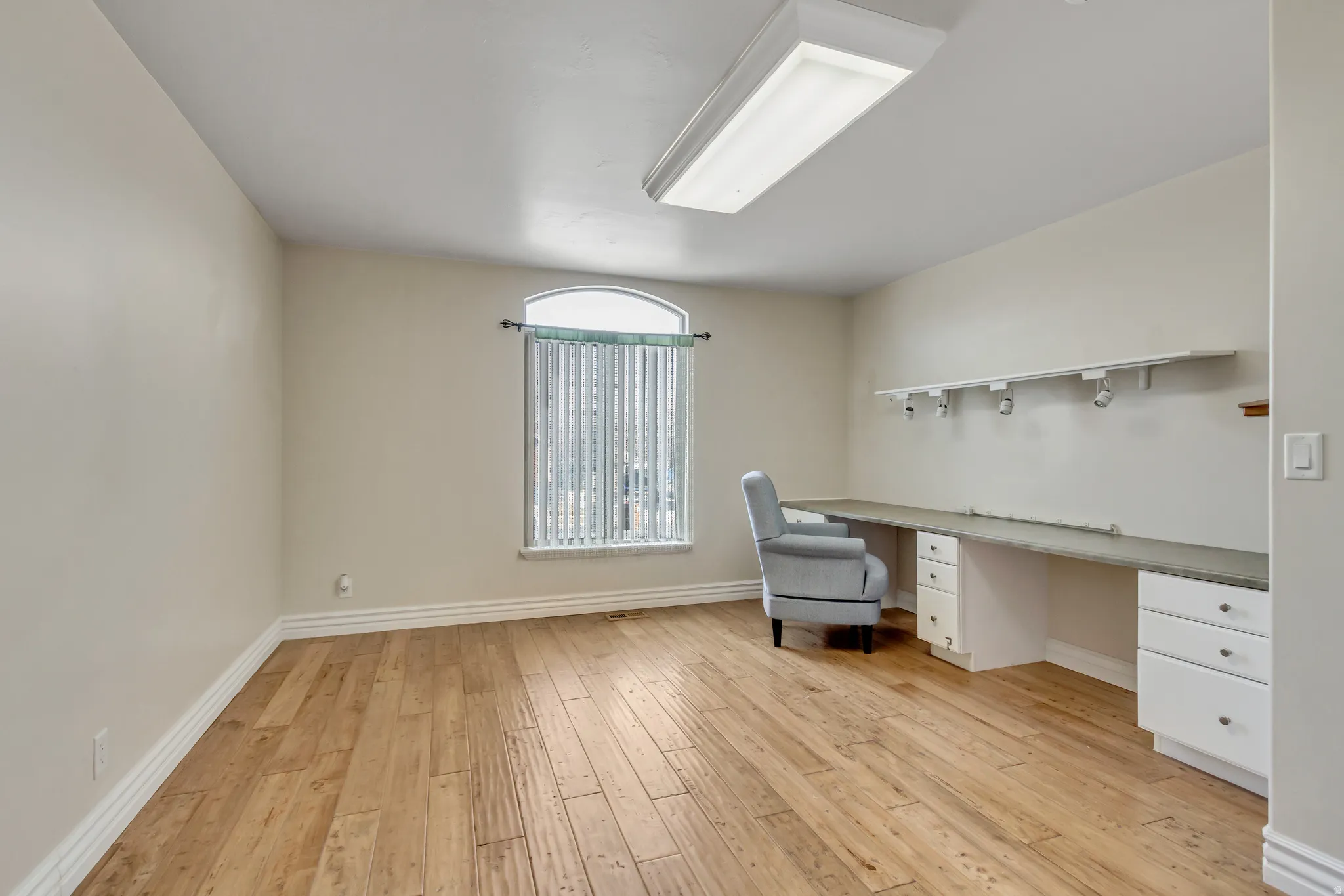 Unfurnished office with built in desk and light wood-style flooring