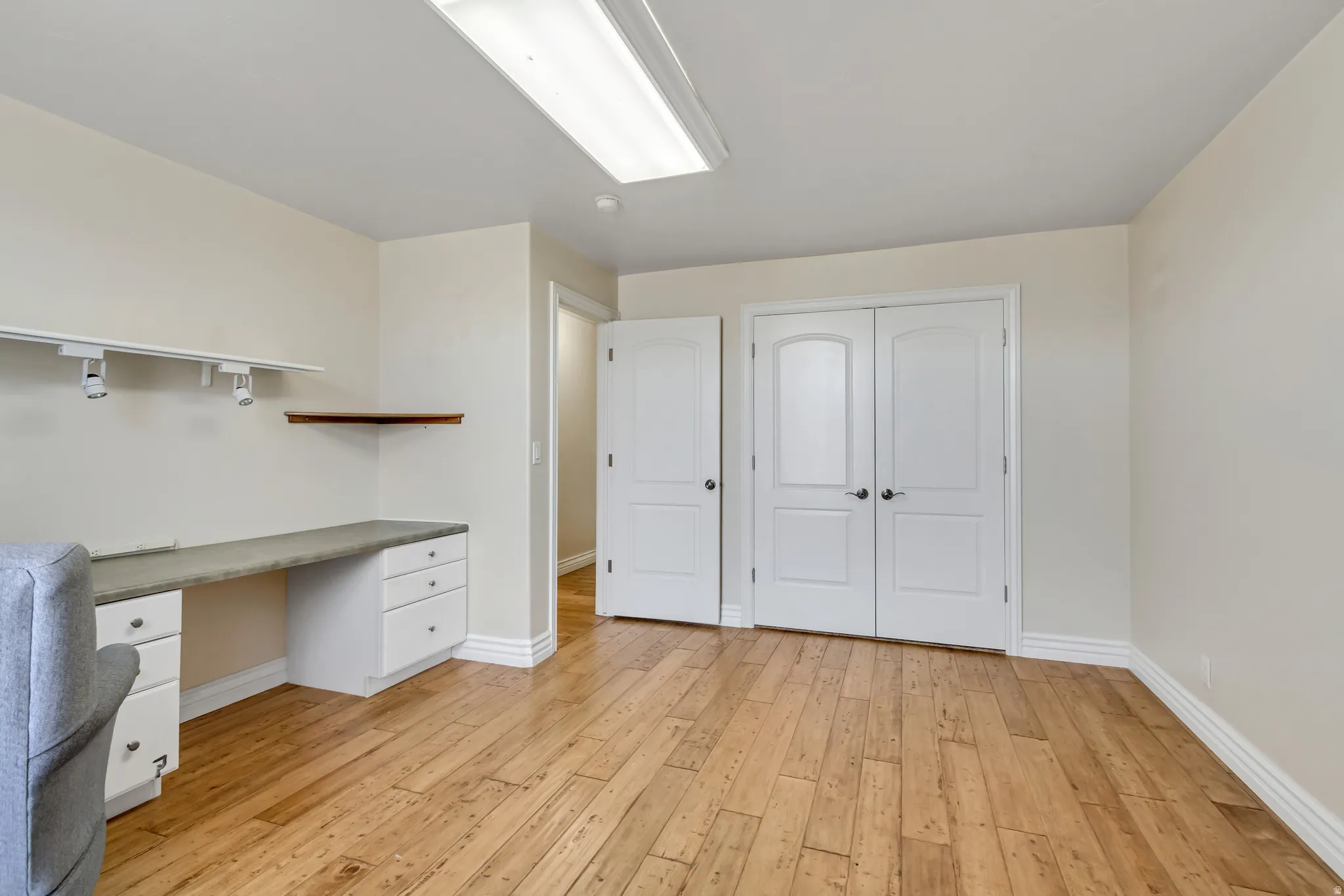 Unfurnished office with built in study area and light wood finished floors