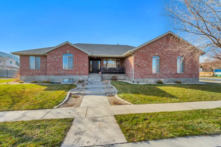 Ranch-style house with brick siding, a front lawn, a porch, and roof with shingles