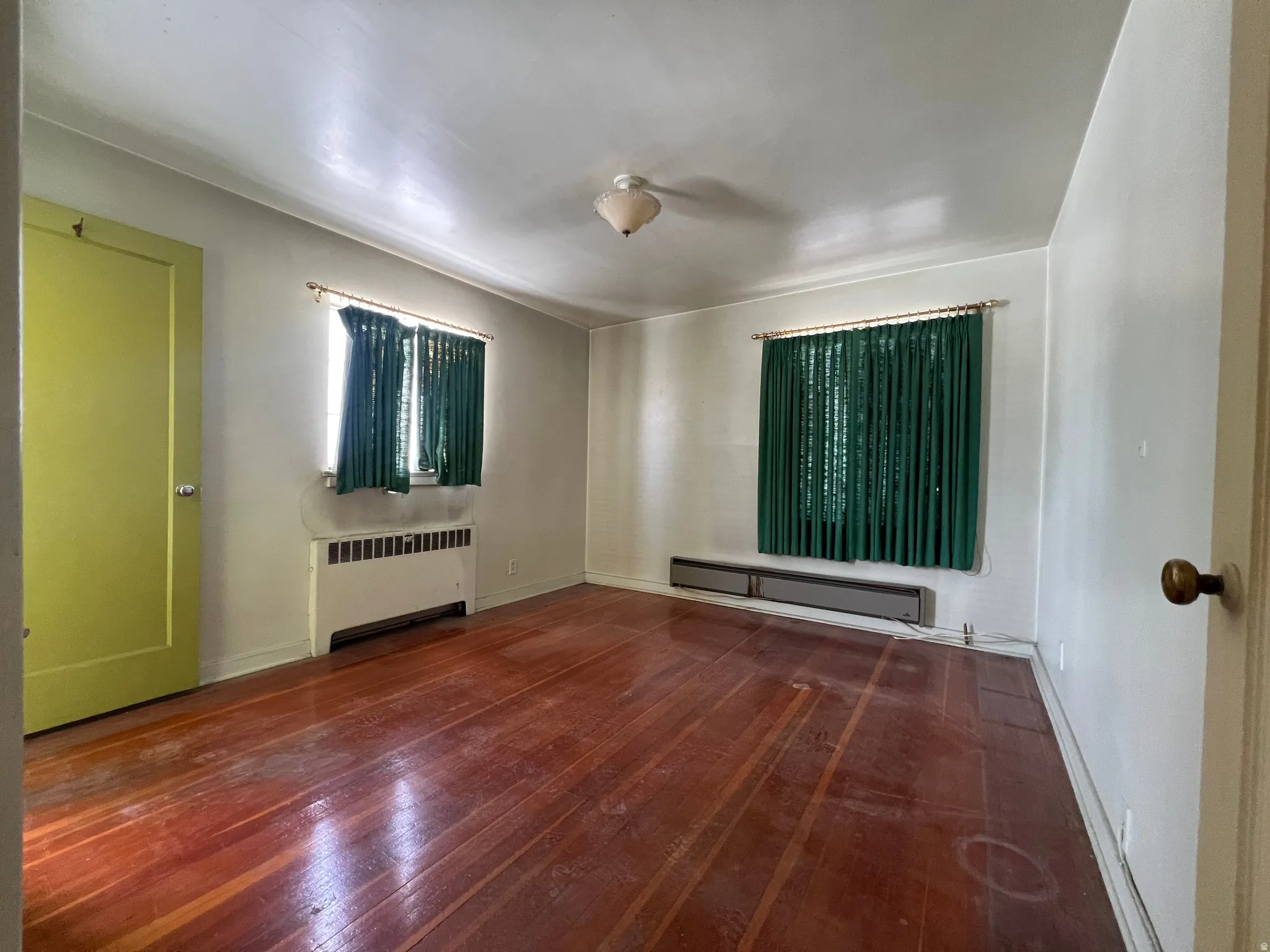 Empty room featuring radiator heating unit, a baseboard heating unit, and dark wood-style floors