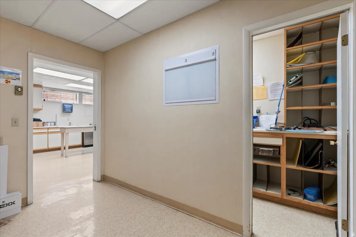 Hallway featuring a drop ceiling and baseboards