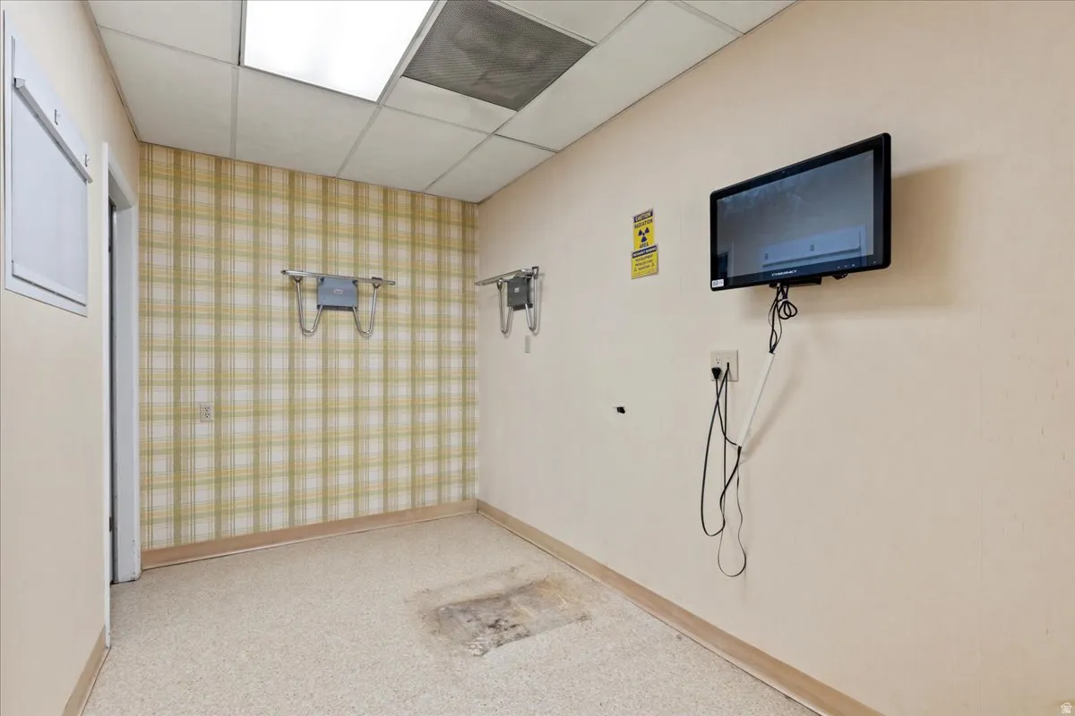 Miscellaneous room with a paneled ceiling, light colored carpet, and wallpapered walls