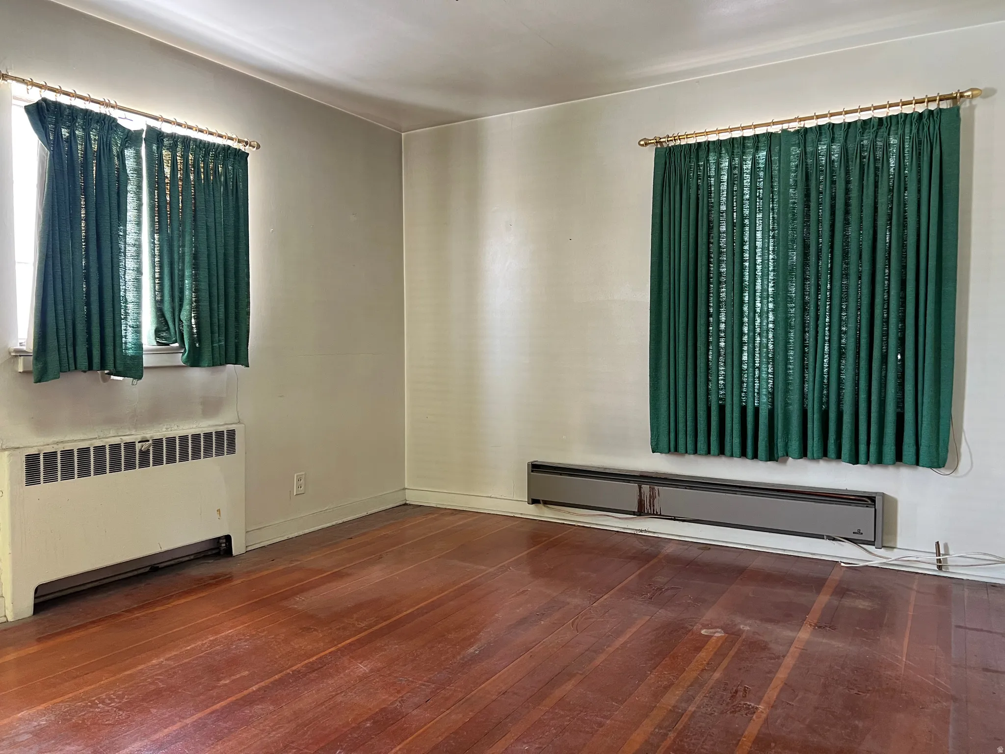 Empty room with radiator, a baseboard heating unit, and dark wood-style flooring