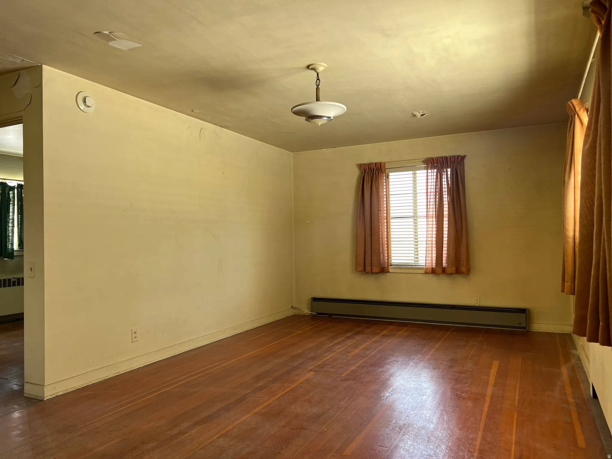 Spare room featuring a baseboard heating unit, dark wood-style floors, and radiator heating unit