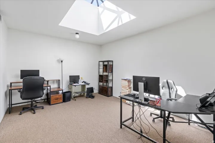 Office area featuring light carpet and a skylight