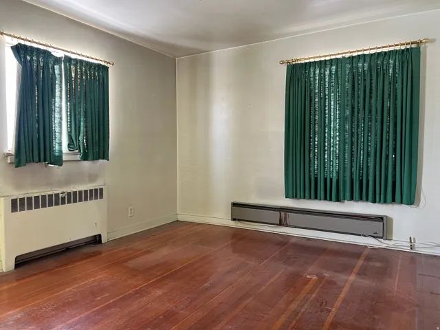 Empty room with radiator, a baseboard heating unit, and dark wood-style flooring
