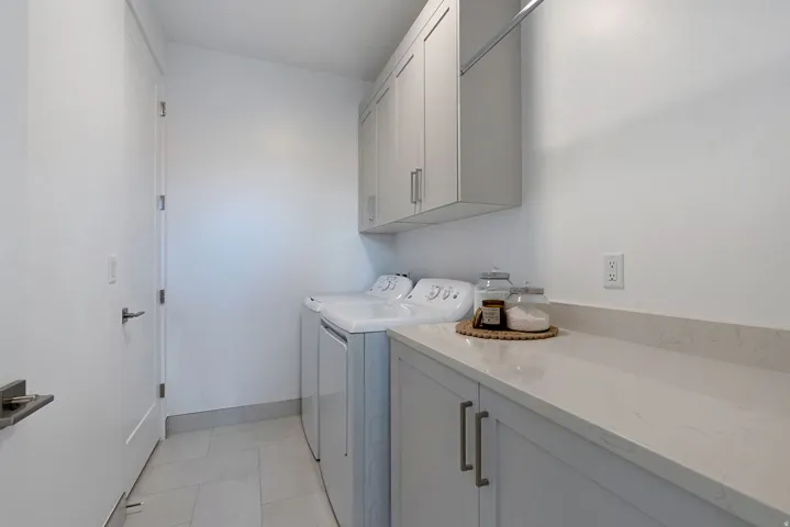 Laundry room featuring washer and dryer, cabinet space, and light tile patterned floors