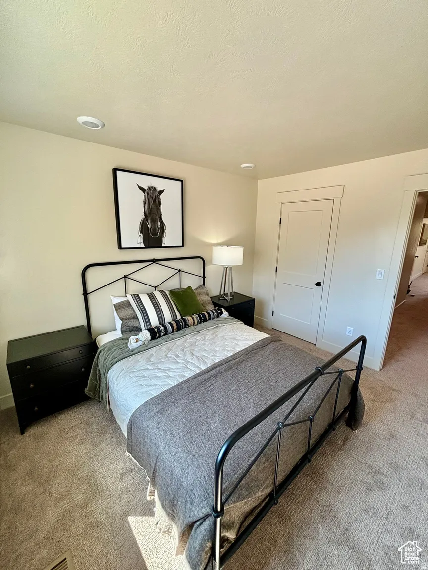 Bedroom with light colored carpet and a textured ceiling
