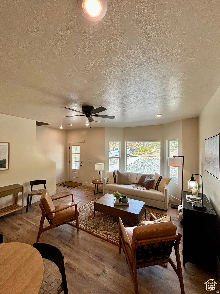 Living area with recessed lighting, wood finished floors, a textured ceiling, and a ceiling fan