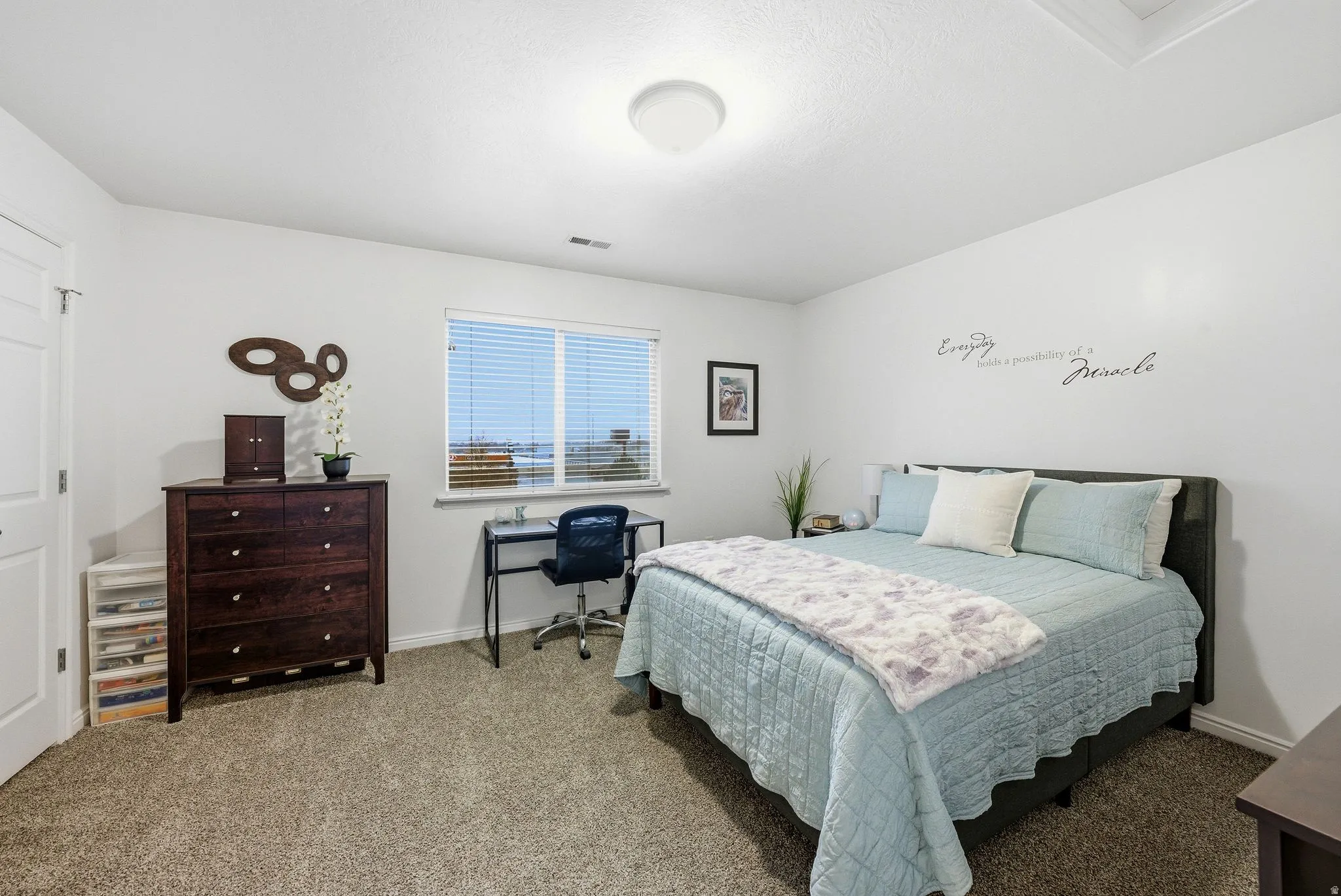 Carpeted bedroom featuring baseboards and a desk