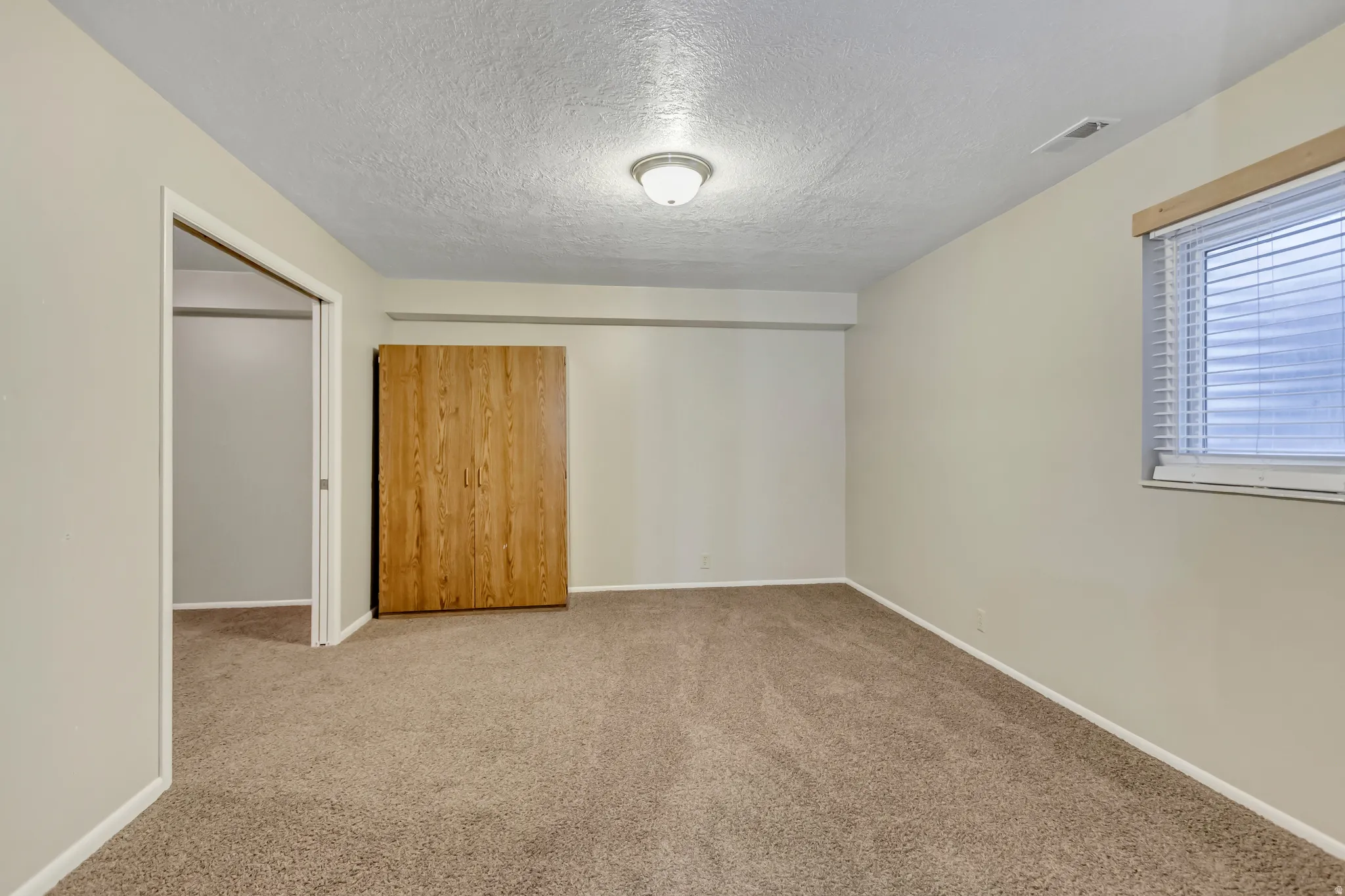 Unfurnished bedroom with a textured ceiling, carpet flooring, and a closet
