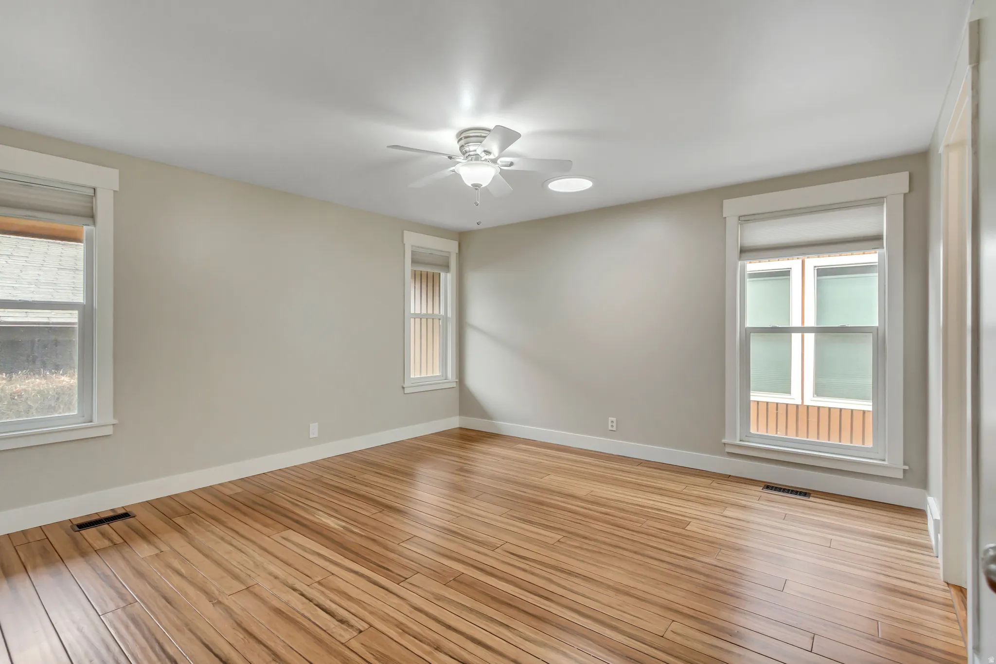 Master suite with light wood-style floors and a ceiling fan