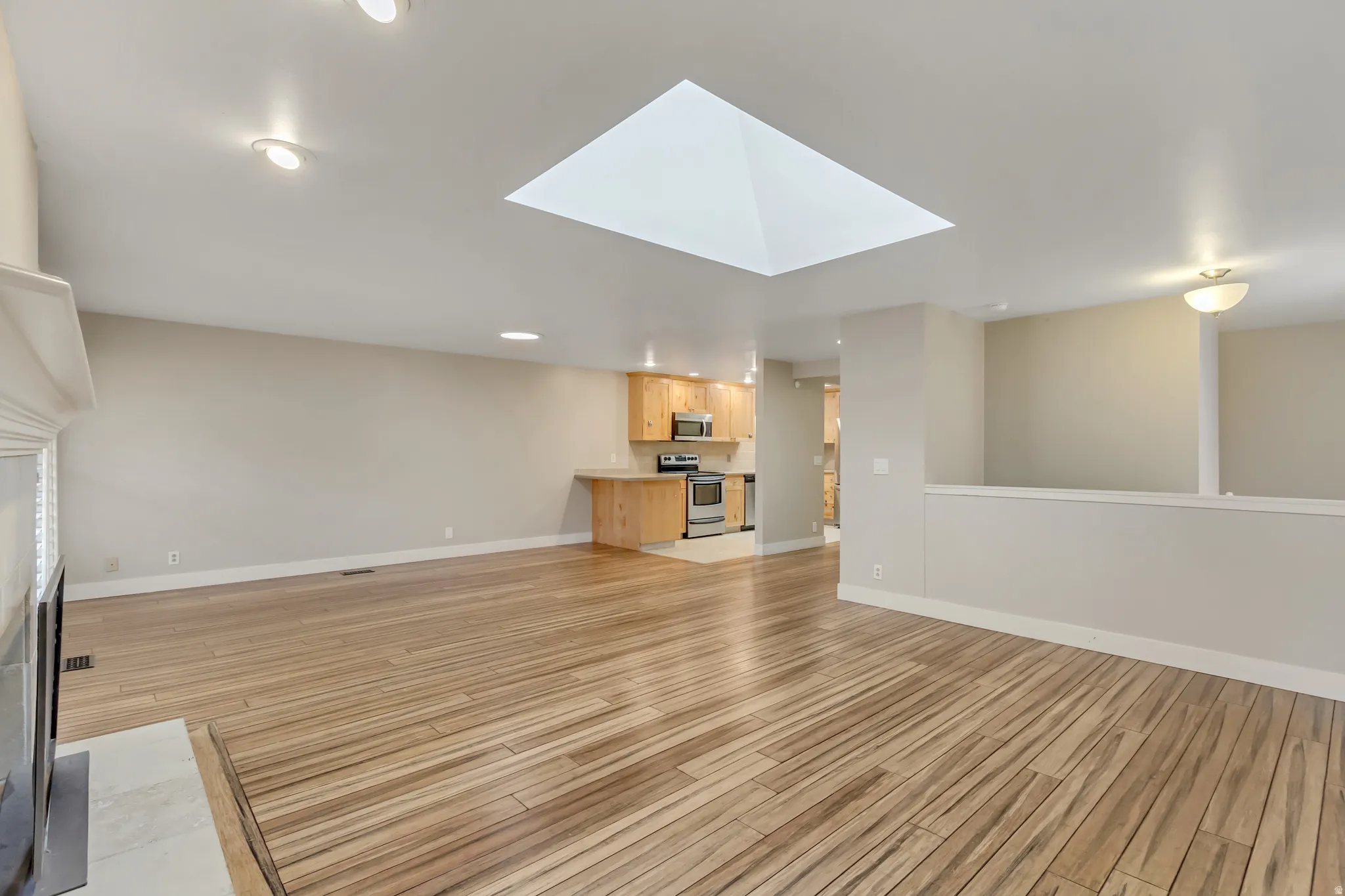 Unfurnished living room featuring a skylight, light wood-type flooring, a fireplace, and recessed lighting