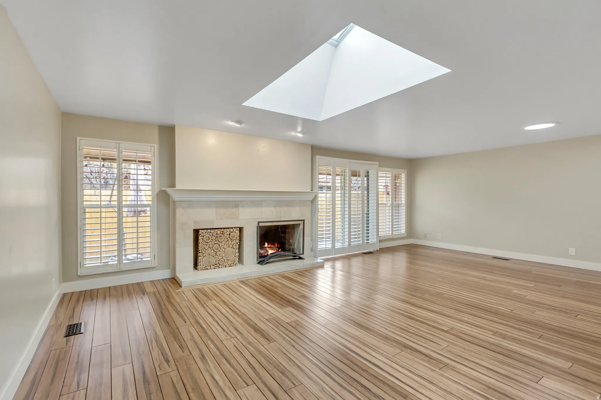 Unfurnished living room with a skylight, a fireplace, and light wood-type flooring
