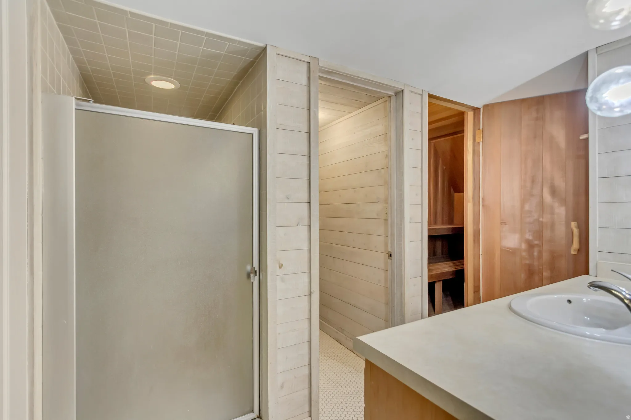 Bathroom featuring vanity, a stall shower, wooden walls, and recessed lighting