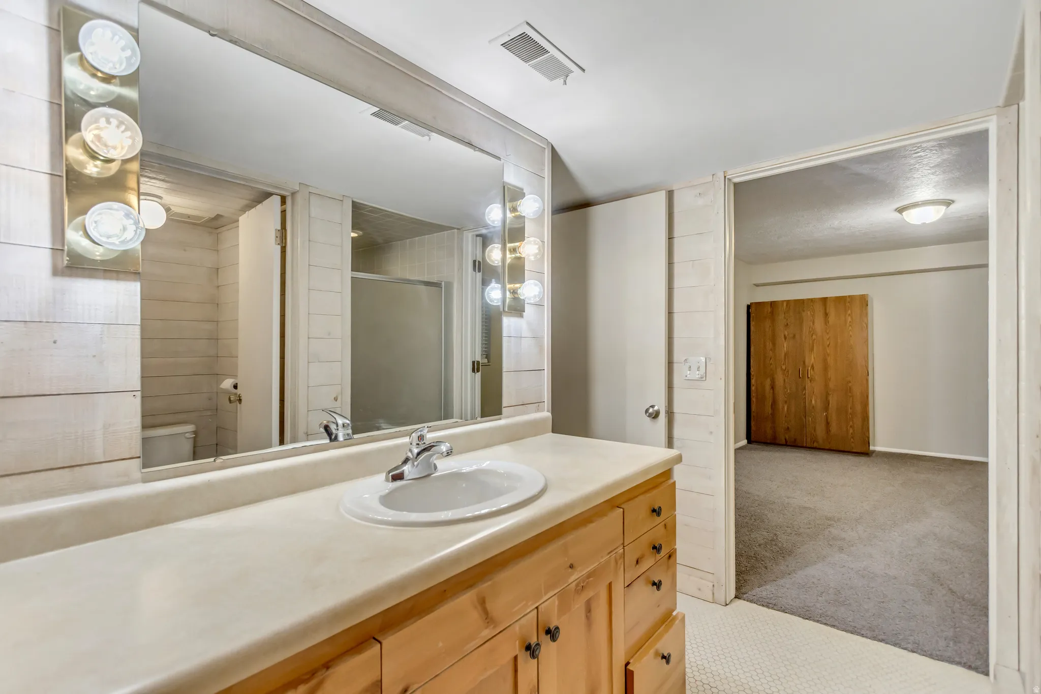Full bath featuring a shower stall, light carpet, and vanity