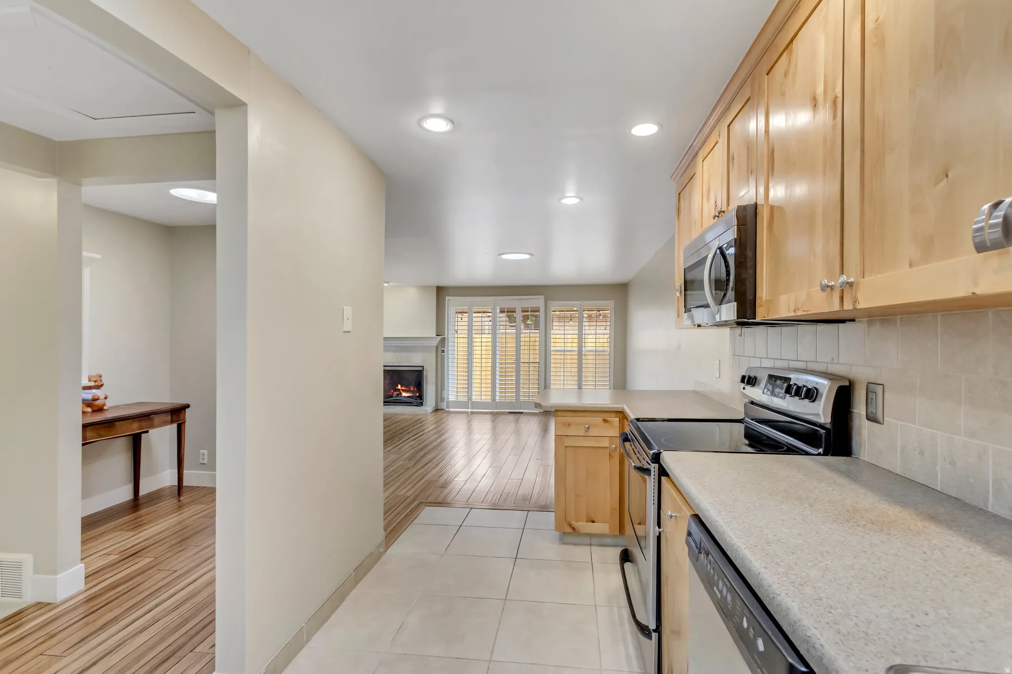 Kitchen featuring appliances with stainless steel finishes, light brown cabinets, backsplash, and light tile patterned floors.