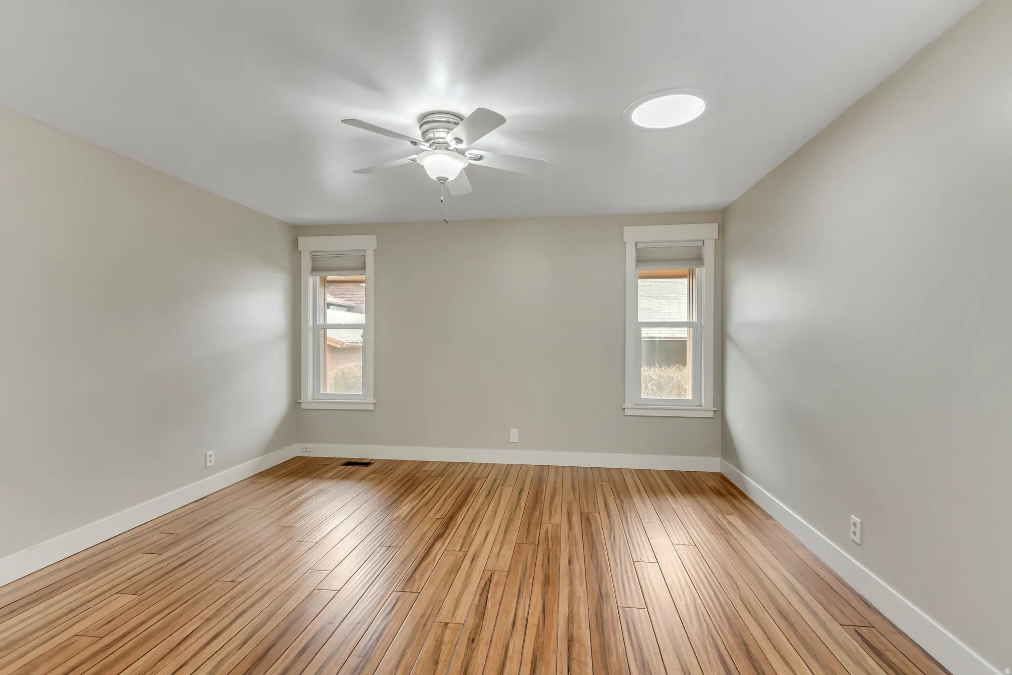 Empty room featuring healthy amount of natural light, light wood-type flooring, and ceiling fan